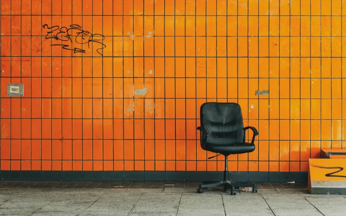 Ein leerer Bürostuhl vor einer orange gekachelten Wand