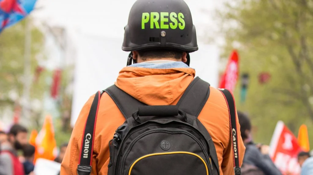 Ein Journalist mit Helm auf dem Kopf auf einer Demo