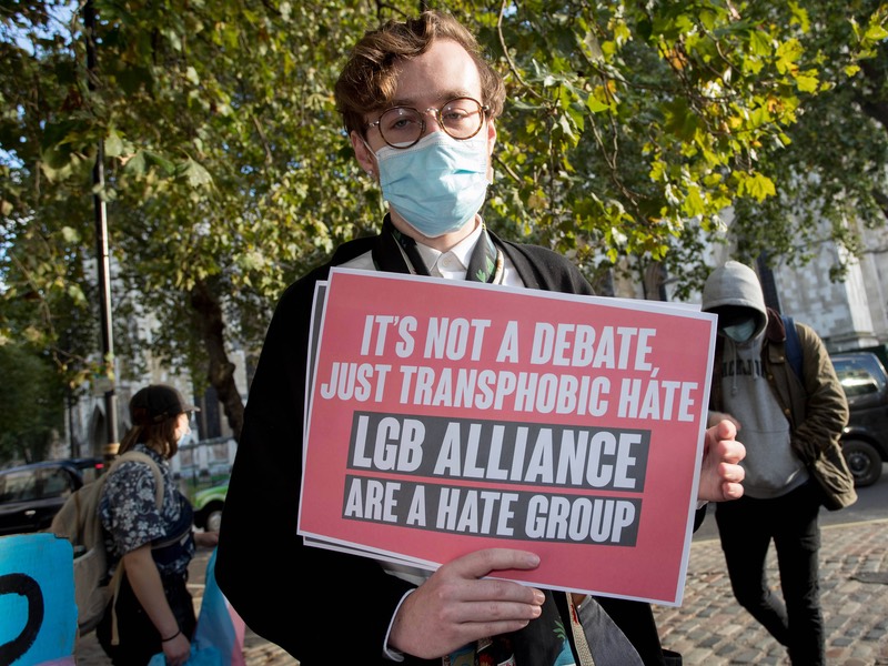 Protest mit einem Plakat und der Aufschrift: "It's not a debate just transphobic hate. LGB Alliance are a hate group"