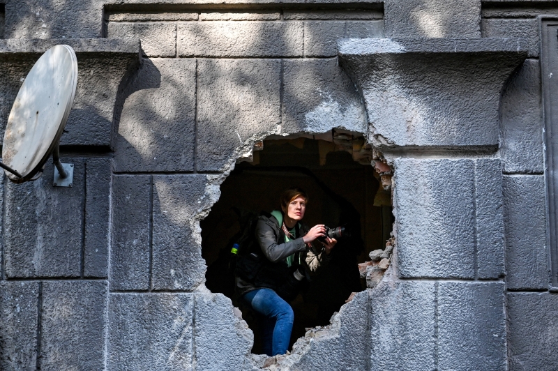 Ein Journalist lugt aus dem Loch in der Wand eines Wohnhauses, das durch einen Raketenangriff der russischen Truppen beschädigt wurde, in Zaporizhzhia im Südosten der Ukraine. Die Folgen des morgendlichen Raketenangriffs der russischen Truppen in Saporischschja