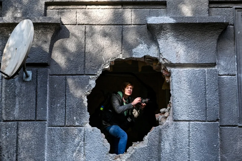 Ein Journalist lugt aus dem Loch in der Wand eines Wohnhauses, das durch einen Raketenangriff der russischen Truppen beschädigt wurde, in Zaporizhzhia im Südosten der Ukraine. Die Folgen des morgendlichen Raketenangriffs der russischen Truppen in Saporischschja