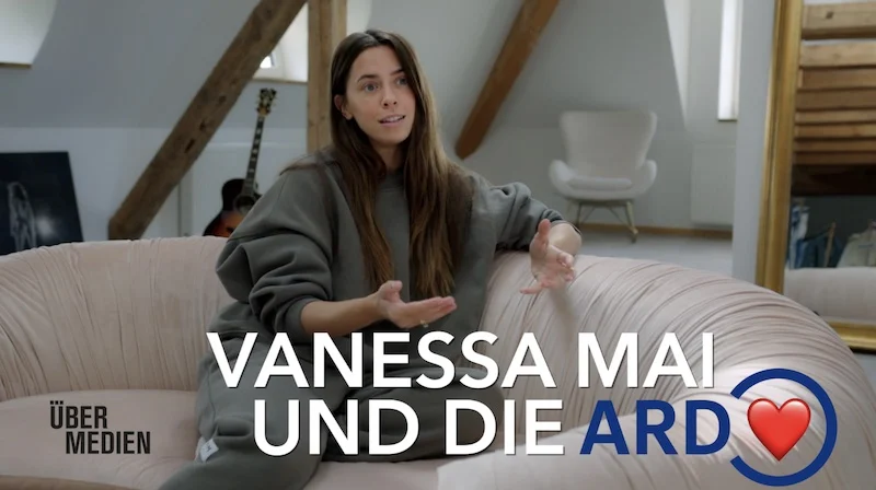 Vanessa Mai sitzt im Jogginganzug auf einem Sofa.