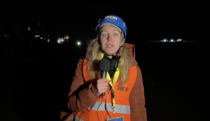 Reporterin steht im Dunklen am Tagebau in Lützerath