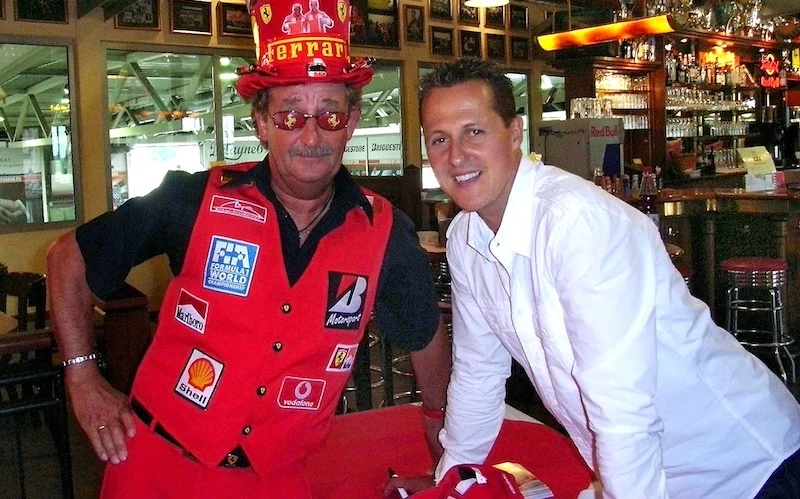 Reiner Ferling (links) vom Schumacher-Fanclub, in Fan-Montur und mit Schumacher-Zylinder, neben Michael Schumacher.