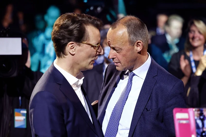 Friedrich Merz und Hendrik Wüst stehen sich Stirn an Stirn gegenüber