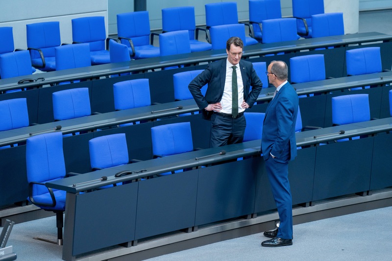 Hendrik Wüst und Friedrich Merz unterhalten sich vor der leeren Bundesrats-Bank im Bundestag