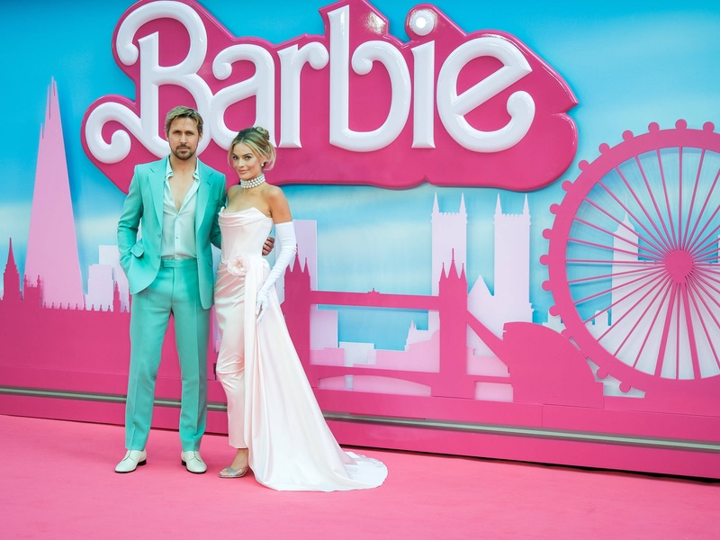 Ryan Gosling und Margot Robbie posieren vor dem Barbie-Logo 