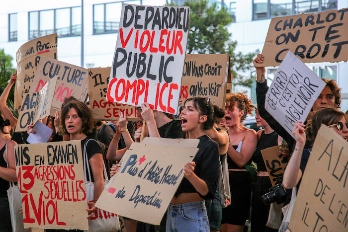 Frauen halten bei einer Demonstration gegen Gérard Depardieu Schilder hoch.
