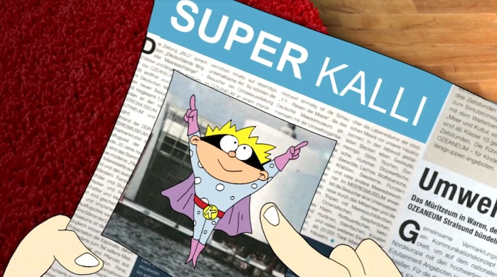 Screenshot einer Szene der Serie "Super-Kalli" im "Sandmännchen". Zu sehen ist eine Zeitungsseite, auf der "Super-Kalli" abgebildet ist.