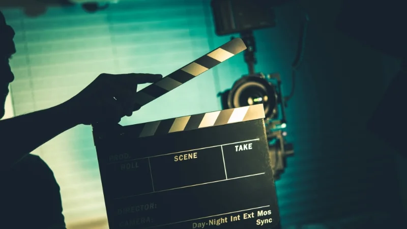 Mann mit Filmklappe vor Kamera