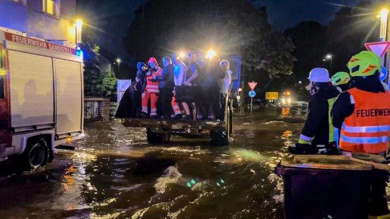 Ein Radlader rettet auf seiner Schaufel mehrere Menschen aus der der Flut