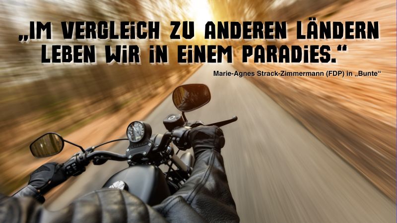 Angeschnittenes Motorrad, das schnell auf einer Landstraß fährt mit Zitat von Marie-Agnes Strack-Zimmermann: „Im Vergleich zu anderen Ländern leben wir in einem Paradies.“