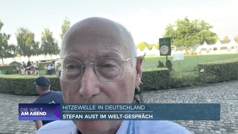 Der Journalist Stefan Aust steht am Rande des Aachener Pferdestadions und spricht in sein Smartphone. Sein Mund wird von einer Einblendung des Senders verdeckt.