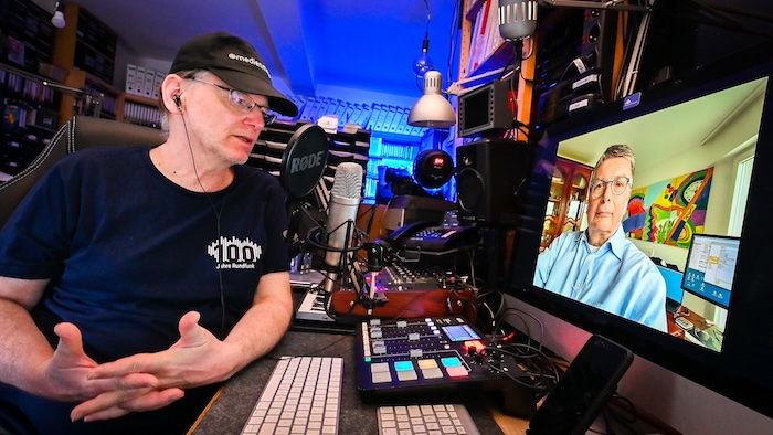 Jörg Wagner am Mikro in seinem Studio. Vor ihm, auf einem Bildschrim, ist sein Interviewpartner zu sehen.