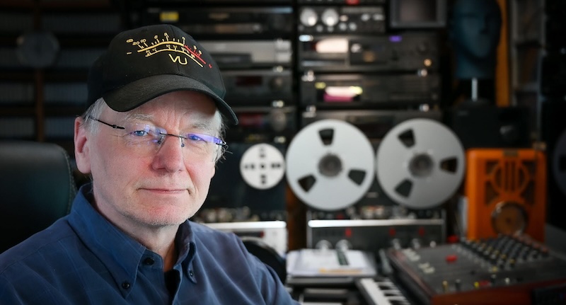Der Medienjournalist Jörg Wagner in seinem Studio. Hinter ihm ein Mischpult und diverse Verstärker und ein Tonbandgerät.
