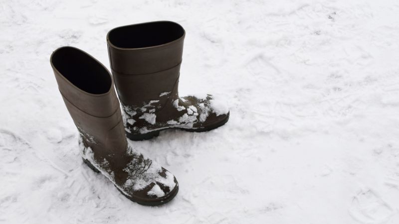 Schwarze Gummistiefel im Schnee.