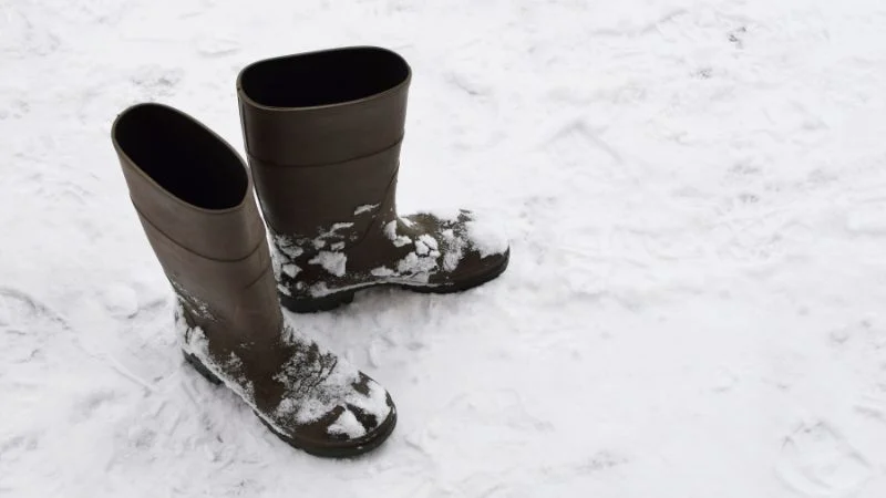 Schwarze Gummistiefel im Schnee.