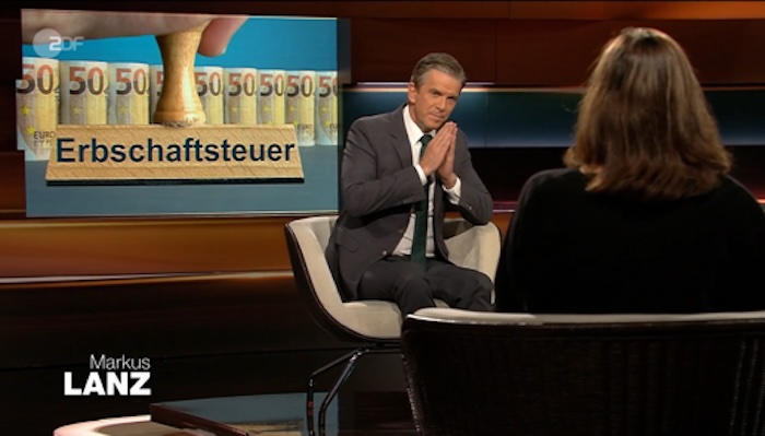 Talksrunde bei „Markus Lanz“, im Hintergrund: sind mehrere gerollte 50-Euro-Scheine zu sehen, davor eine Hand mit einem Stempfel, auf dem „Erbschaftssteuer steht“.