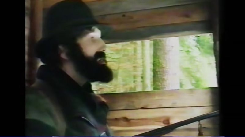 Ein angeblicher Jäger sitzt mit einem Gewehr in einem Hochsitz. Die Szene ist Teil einer Fake-Reportage von Michael Born.