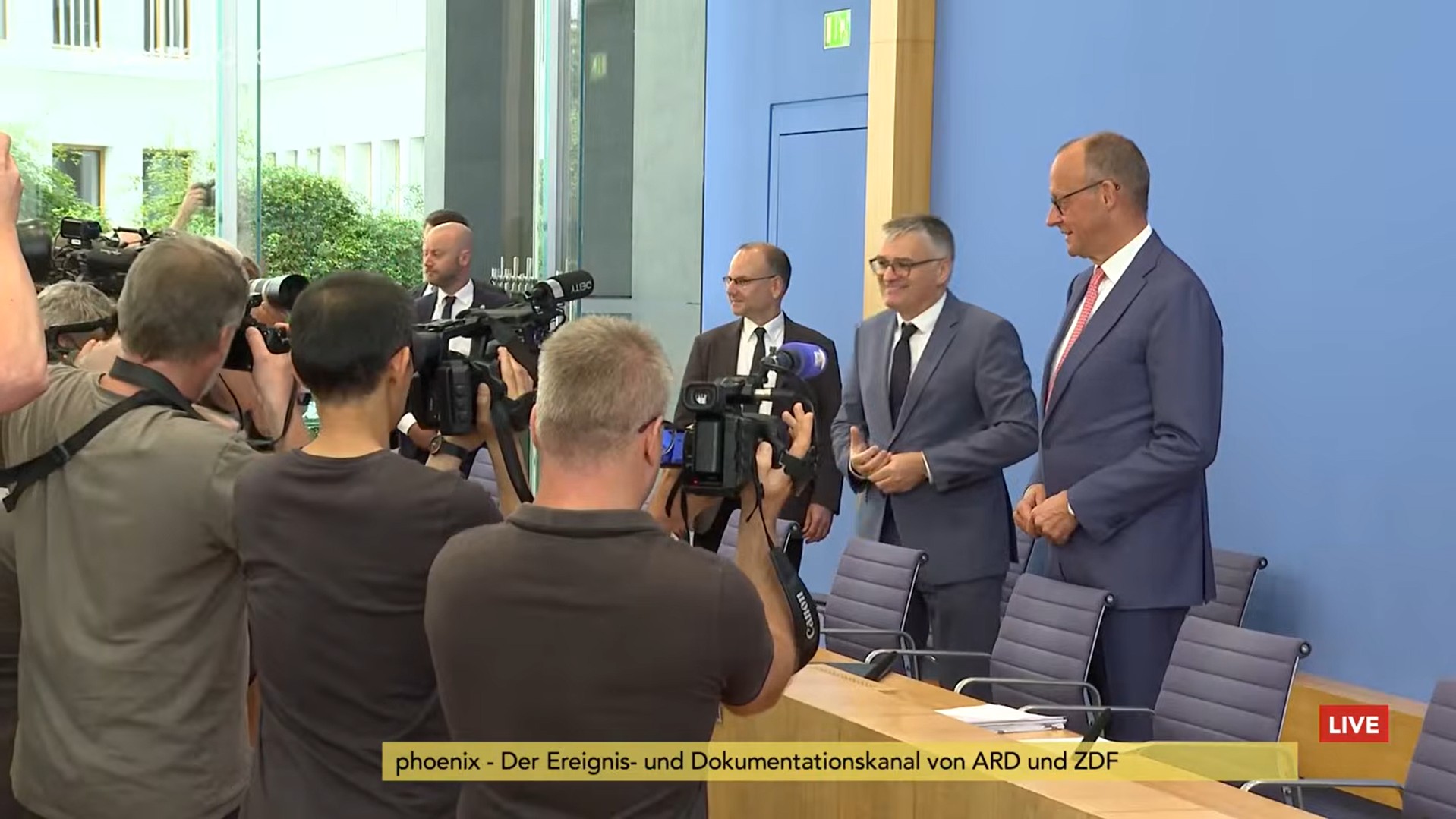 Bundeskanzler Merz und sein Sprecher vor Fotografen in der Bundespressekonferenz in Berlin