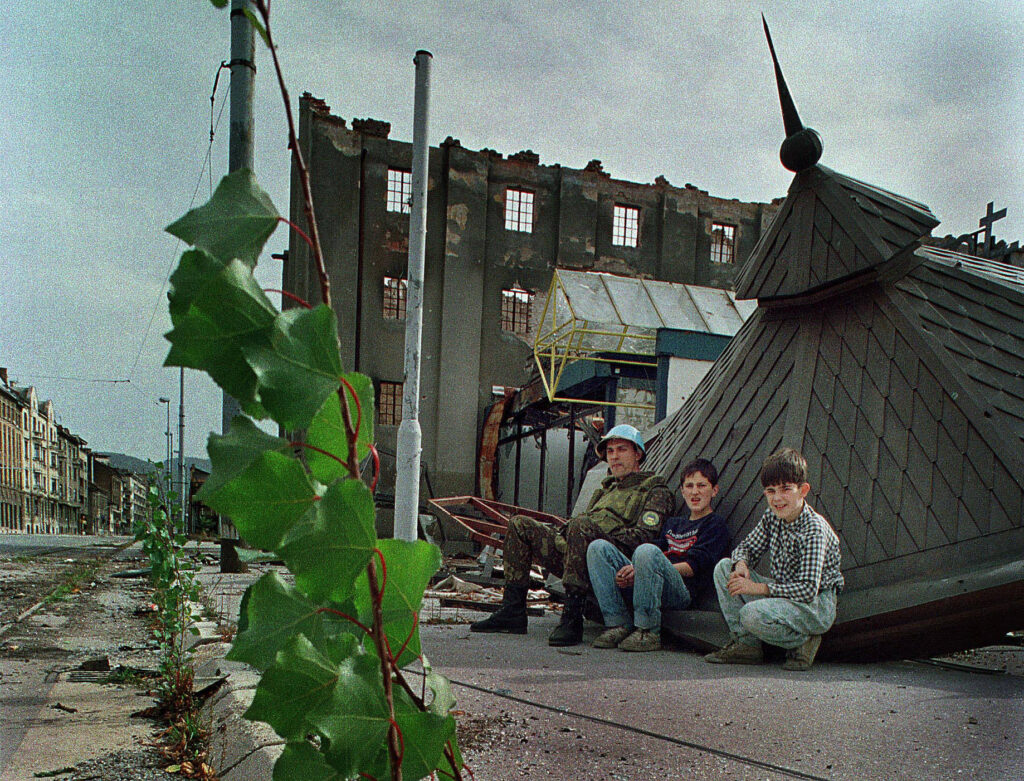 Ein ukrainischer Blauhelmsoldat sitzt mit zwei Jungen während der Belagerung von Sarajevo am Ende der berüchtigten „Sniper Alley“. Heckenschützen nahmen die Straße häufig unter Beschuss.