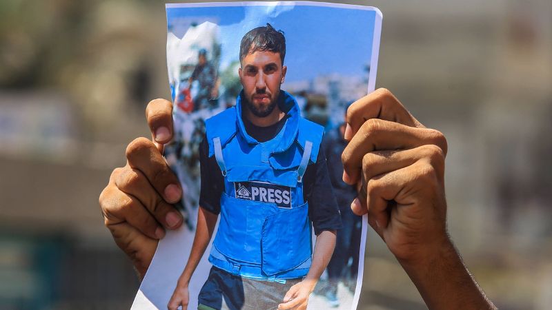 Zwei Hände halten ein Foto, das einen im Gaza-Krieg getöteten Journalisten zeigt