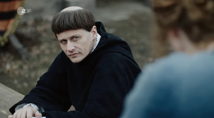 Luther sitzt auf einer Bank und schaut grimmig.