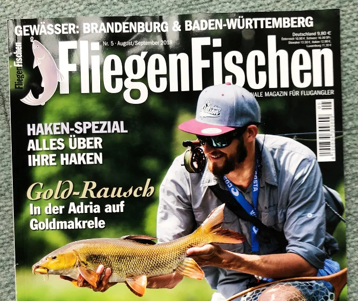 Angler mit Kappe und Sonnenbrille, der an einem Fluss einen Karpfen in der Hand hält