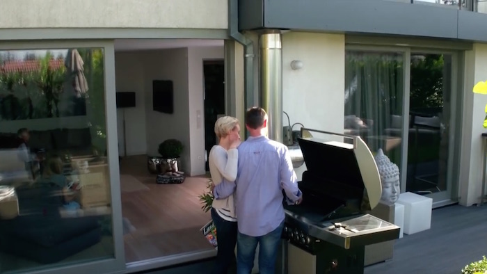 Standbild aus dem Imagefilm der Funke Mediengruppe: Mann und Frau stehen auf einer Terrasse an einem großen Grill, Arm in Arm. Der Mann grillt.