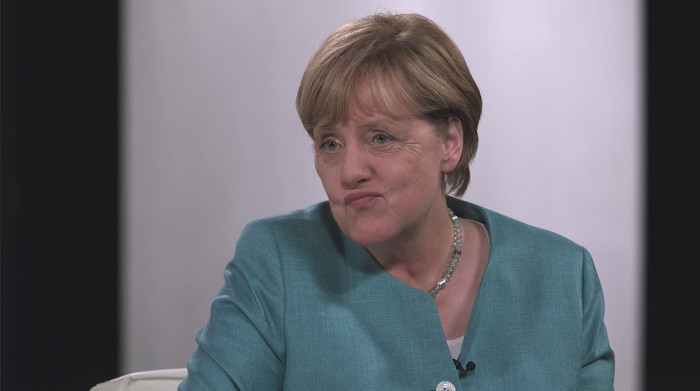 Angela Merkel zieht die Mundwinkel nach unten zum Gesicht eines schlecht gelaunten Smileys
