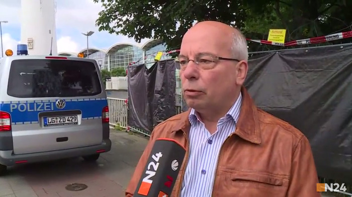 Rainer Wendt im Interview mit N24: Mann, Glatze, Brille, braune Lederjacke, blaues Hemd, steht vor einem Polizeiwagen.