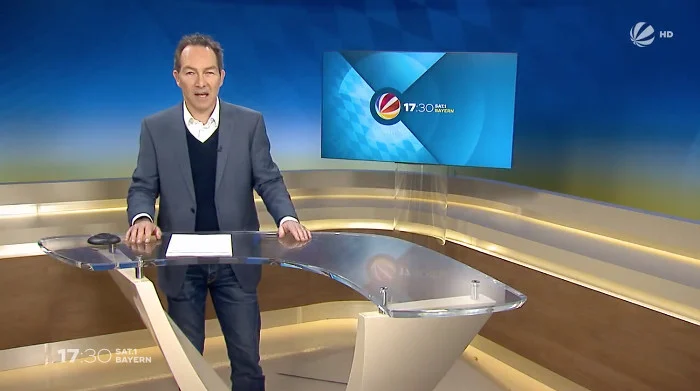 Mann im grauen Anzug im Sat.1 Bayern Studio
