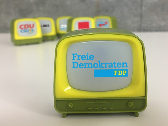 Kleiner Fernseher mit dem Logo der FDP vorne und im Hintergrund fünf weitere Fernseher mit den Logos der SPD, Union, Grünen, Linken und AfD.